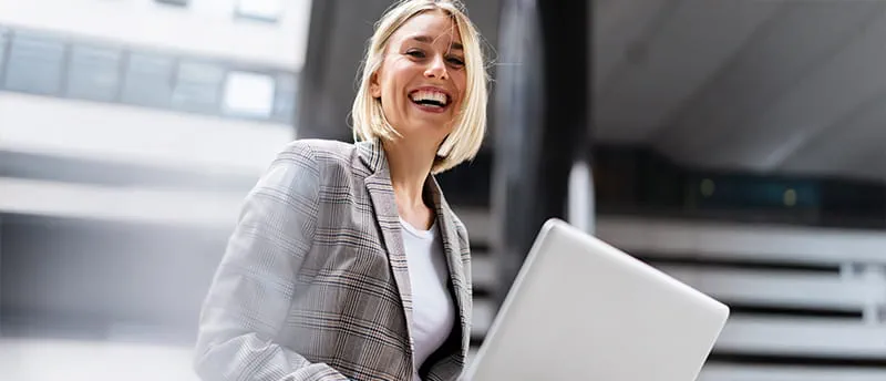 Blonde Frau sitzt am Laptop und lacht. Blonde Frau sitzt am Laptop und lacht.