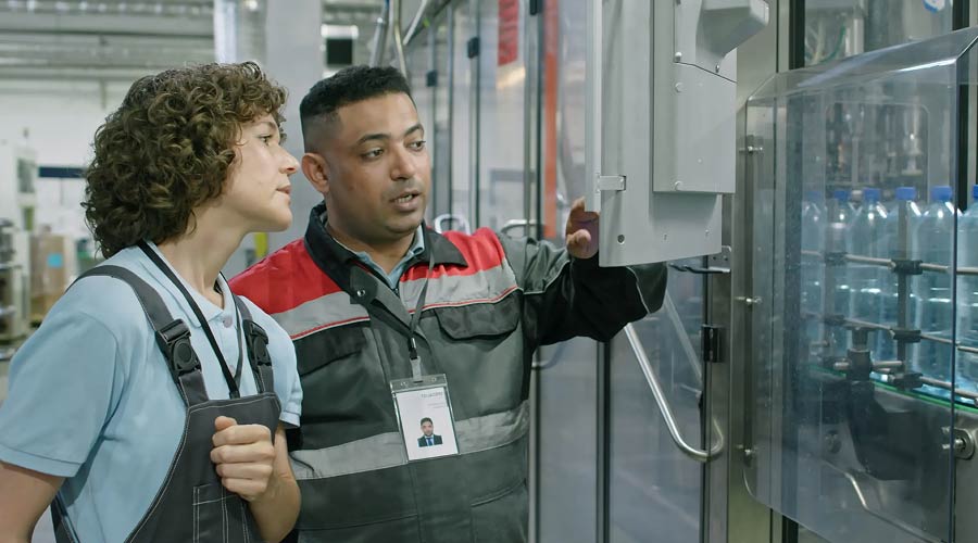 Zwei Männer bedienen eine Maschine in einer Fabrik Zwei Männer bedienen eine Maschine in einer Fabrik
